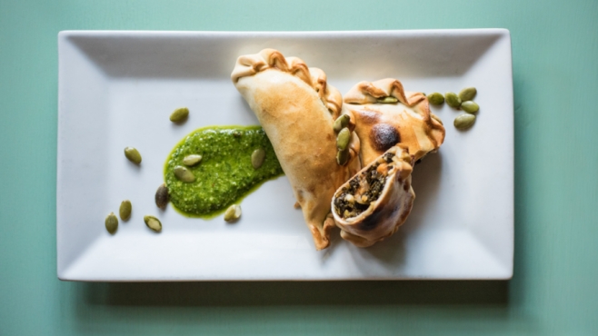 Kale and Sweet Potato empanadas with pumpkin seed chimichurri on a plate 